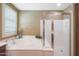 Bright bathroom featuring a soaking tub, glass enclosed shower, white cabinets, and neutral paint at 3521 N Hooper St, Buckeye, AZ 85396