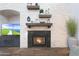 Close-up of a cozy fireplace with a black granite surround and floating shelves showcasing decorative items at 3521 N Hooper St, Buckeye, AZ 85396