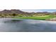 Scenic golf course view with a tranquil lake, lush green fairways, and stunning mountain backdrop at 3521 N Hooper St, Buckeye, AZ 85396