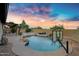 Beautiful backyard featuring a custom pool with rock accents, palm trees, and a covered patio area at 4329 W Electra Ln, Glendale, AZ 85310