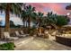 Inviting backyard oasis with palm trees, lounge chairs, fire pit, and outdoor kitchen under a vibrant, colorful sunset sky at 4519 N 29Th Way, Phoenix, AZ 85016