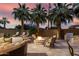 Luxurious backyard with a fire pit, outdoor seating, a built-in grill, and swaying palm trees under a colorful sky at 4519 N 29Th Way, Phoenix, AZ 85016