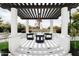 Elegant outdoor gazebo with white columns and dark wood pergola featuring stylish seating around a small, round table at 5 E Oakwood Hills Dr, Chandler, AZ 85248