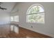 Bright bedroom featuring a large arched window with views of lush greenery and beautiful hardwood flooring at 533 N Cobblestone St, Gilbert, AZ 85234