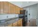 A kitchen with light wood cabinets, granite countertops, and black appliances provides a functional cooking space at 533 N Cobblestone St, Gilbert, AZ 85234