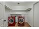 Functional laundry room features red washer and dryer, with ample shelving for storage at 533 N Cobblestone St, Gilbert, AZ 85234