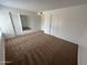 A sunlit bedroom featuring neutral carpet, a mirror, and three doorways, offering a calm and inviting atmosphere at 6842 S 42Nd Pl, Phoenix, AZ 85042