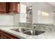 Close up of a stainless steel kitchen sink with granite countertops and brown cabinetry at 8450 S Stephanie Ln, Tempe, AZ 85284