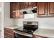 Modern kitchen features a black stove top, granite counters and brown wood cabinets at 8450 S Stephanie Ln, Tempe, AZ 85284