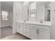 Spacious bathroom features dual sinks, white cabinets, large mirrors, and natural light from the window at 9222 W Roma Ave, Phoenix, AZ 85037