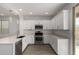 Well-lit kitchen boasts stainless steel appliances, white cabinets, quartz countertops, and backyard access at 9222 W Roma Ave, Phoenix, AZ 85037
