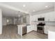 Bright kitchen with stainless steel appliances, white cabinets, breakfast bar, and open access to the living room at 9222 W Roma Ave, Phoenix, AZ 85037