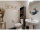 Cozy half bath with pedestal sink, decorative mirror, and wall decor at 9948 W Chipman Rd, Tolleson, AZ 85353