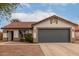 Single-story home with gray garage door, desert landscaping, and a tile roof under a cloudy blue sky at 10625 E Bramble Ave, Mesa, AZ 85208