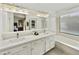 Bathroom featuring double sinks, white cabinets, bathtub, and plenty of light at 11430 N 109Th St, Scottsdale, AZ 85259