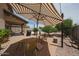 Backyard patio with shade umbrella, chairs, and BBQ creating a relaxing space for outdoor entertainment and relaxation at 11563 W Jefferson St, Avondale, AZ 85323