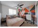 Bedroom boasts unique geometric wall design, comfortable bed, and functional workspace at 11563 W Jefferson St, Avondale, AZ 85323