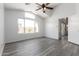 Bright bedroom featuring a large window, ceiling fan, and modern wood-look flooring at 11622 W Buck Mountain Ct, Surprise, AZ 85378