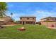 Enjoy the backyard with fire pit, lush lawn, and the home's exterior, offering a cozy outdoor space at 12325 W Canterbury Dr, El Mirage, AZ 85335