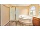 Bright bathroom featuring a soaking tub, frosted glass shower and wood look floors at 12325 W Canterbury Dr, El Mirage, AZ 85335