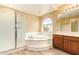 Bathroom featuring a soaking tub, shower, and framed window with views of the outdoors at 12325 W Canterbury Dr, El Mirage, AZ 85335