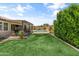 Lush backyard featuring a covered patio, outdoor kitchen, swimming pool, and manicured green lawn at 12516 W Mclellan Ct, Glendale, AZ 85307