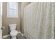 Bathroom features a toilet, shower with patterned curtain and window with plantation shutters at 12516 W Mclellan Ct, Glendale, AZ 85307