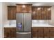 Modern refrigerator complemented by dark wood cabinetry, white countertops, and mosaic backsplash at 12516 W Mclellan Ct, Glendale, AZ 85307
