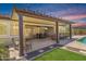 This covered patio features an outdoor kitchen with bar seating and a dining table, located next to a refreshing pool at 12516 W Mclellan Ct, Glendale, AZ 85307