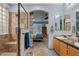 Bathroom featuring dual sinks, walk-in glass shower, and view to bedroom at 13629 W San Miguel Ave, Litchfield Park, AZ 85340