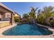 Inviting pool with a rock waterfall, lush landscaping, and nearby palm trees at 13629 W San Miguel Ave, Litchfield Park, AZ 85340