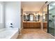Bright bathroom with double vanity sinks, tub, and sliding door closet at 16071 W Sherman St, Goodyear, AZ 85338