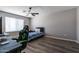 This bedroom features wood floors, a ceiling fan, blinds, and a gaming chair at 16071 W Sherman St, Goodyear, AZ 85338
