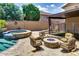 Relaxing backyard patio area with a stone fire pit, comfortable seating, and a sparkling pool nearby at 16141 N 183Rd Dr, Surprise, AZ 85388