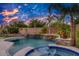 Beautiful backyard pool and spa, complete with stone accents, palm trees, and colorful sunset skies at 16141 N 183Rd Dr, Surprise, AZ 85388