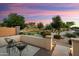 A dusk view of backyard patio with comfortable seating, scenic greenery, and landscape lighting at 16158 W Coronado Rd, Goodyear, AZ 85395
