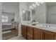 Bathroom boasting double sinks with a dark vanity, framed mirrors, and access to the main bedroom at 16158 W Coronado Rd, Goodyear, AZ 85395