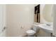 This powder room features decorative art, a round mirror, and pedestal sink with modern fixtures and bright, neutral walls at 16158 W Coronado Rd, Goodyear, AZ 85395