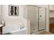 Bathroom featuring a walk-in shower with glass door, large soaking tub, and neutral color palette at 16158 W Coronado Rd, Goodyear, AZ 85395