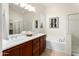 Bright bathroom showcasing double sinks, dark cabinets, soaking tub, and walk-in shower at 16158 W Coronado Rd, Goodyear, AZ 85395