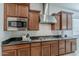 Close-up of the kitchen showcases dark wood cabinets, stainless steel microwave, and gas cooktop on granite counters at 16158 W Coronado Rd, Goodyear, AZ 85395