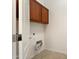 A simple laundry room features overhead cabinets, neutral colors, and the washing machine hookups necessary for this task at 16158 W Coronado Rd, Goodyear, AZ 85395