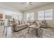 Open-concept living room featuring tile floors, neutral sofas, and modern ceiling fan at 16158 W Coronado Rd, Goodyear, AZ 85395