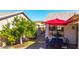 Charming back patio with dining set shaded by a red umbrella and lush landscaping at 1634 E Harwell Rd, Phoenix, AZ 85042