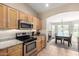 Kitchen showcasing stainless steel oven and microwave, granite countertops, and tile floors leading to breakfast nook at 1634 E Harwell Rd, Phoenix, AZ 85042