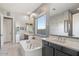 Elegant primary bathroom featuring a soaking tub, dual vanities, and a large window with natural light at 18577 W Coolidge St, Goodyear, AZ 85395