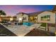 Backyard with a sparkling pool, travertine deck, fire bowls, lounge chairs and lush landscaping at 18577 W Coolidge St, Goodyear, AZ 85395