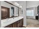 Bathroom featuring double sinks, brown cabinets, and a large framed mirror at 21104 E Poco Calle --, Queen Creek, AZ 85142