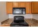 Close-up of black microwave and stove with wood cabinets and neutral countertops at 2210 N 27Th Pl, Phoenix, AZ 85008