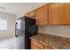 Kitchen with wood cabinets, neutral countertops, and black refrigerator next to dining area at 2210 N 27Th Pl, Phoenix, AZ 85008